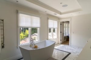 Lutron Silvia shades by the tub in a master bathroom, lowered half way.