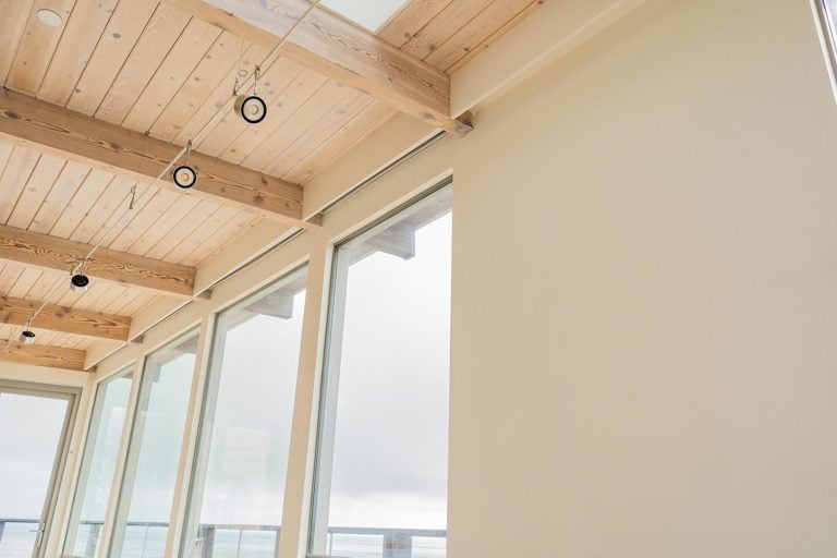 Pocketed shades hidden behind a wood trim above a series of ocean-facing windows